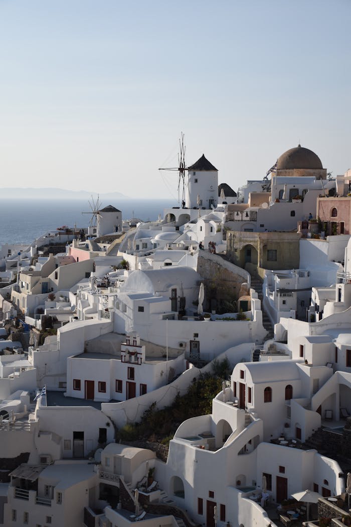 gallery-06 Stunning aerial view of whitewashed architecture in Fira, Greece overlooking the sea under clear skies.